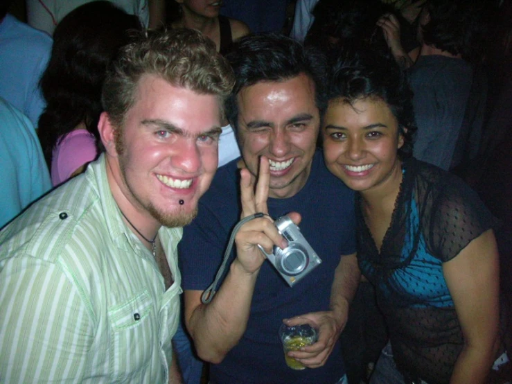 three smiling friends pose for a po at a club