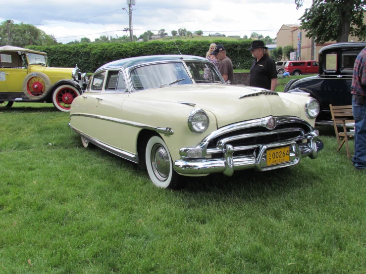 people are looking at classic cars on display