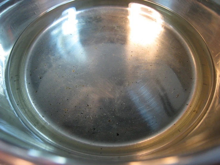 the bottom of a shiny metal bowl with brown spots on it