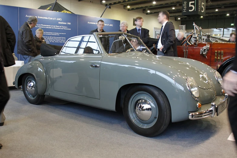 a group of people standing next to an antique car