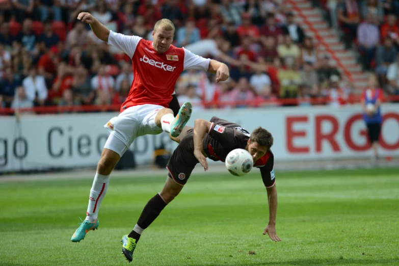 two men playing soccer in front of spectators