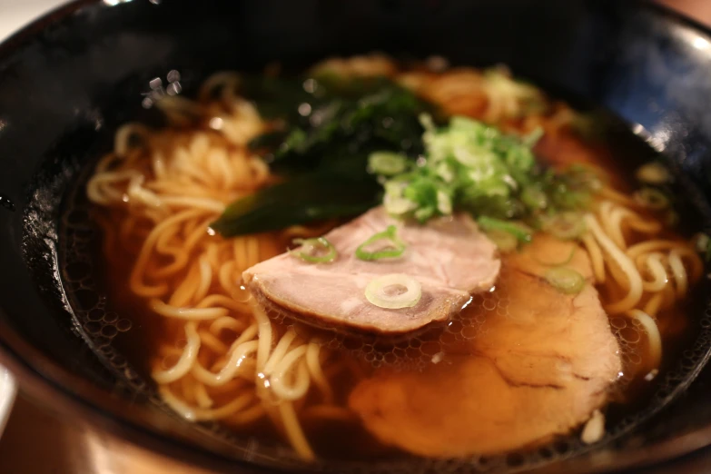 a bowl of noodle, meat and greens