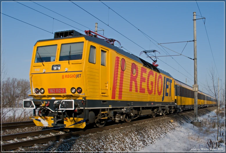 a yellow train car riding down tracks in the snow