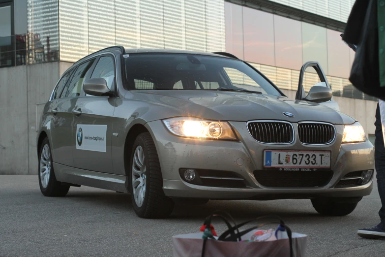 a silver bmw car parked in front of a man