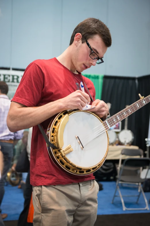 a man in glasses writing on his guitar