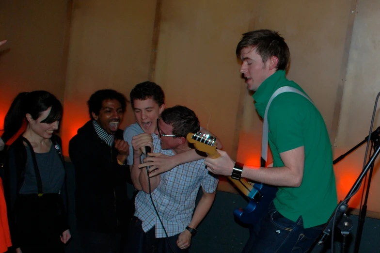 a man holds a guitar while singing to the other people