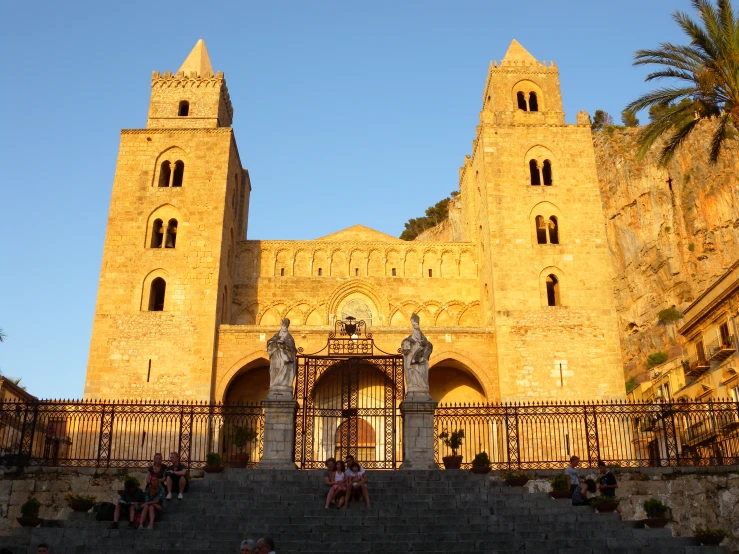 some people sitting on the steps near a castle like building