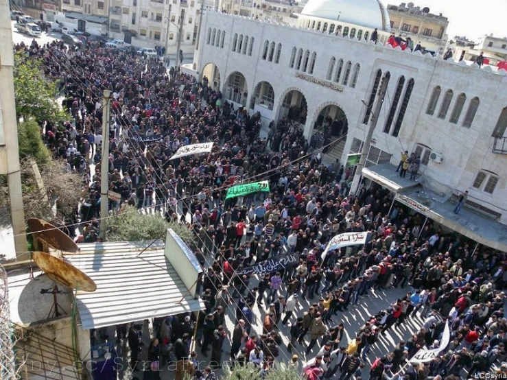 this is a large crowd of people gathered together in front of buildings