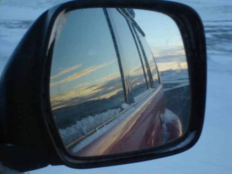 a side mirror of a car driving through the snow