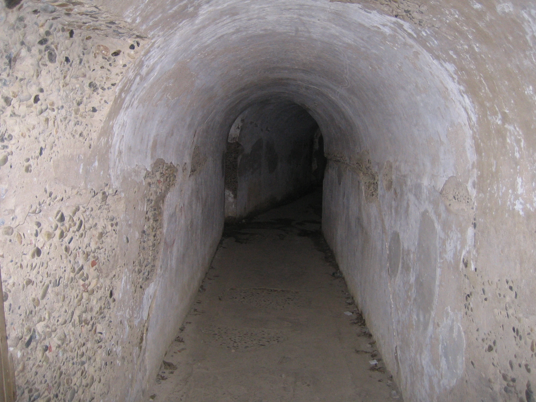 a tunnel with sand and stones between the walls