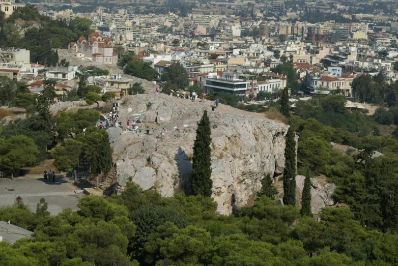 a city skyline, with a hill covered in trees and lots of buildings