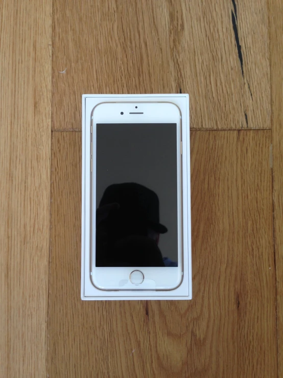 an iphone with a black and white face displayed on a wooden floor