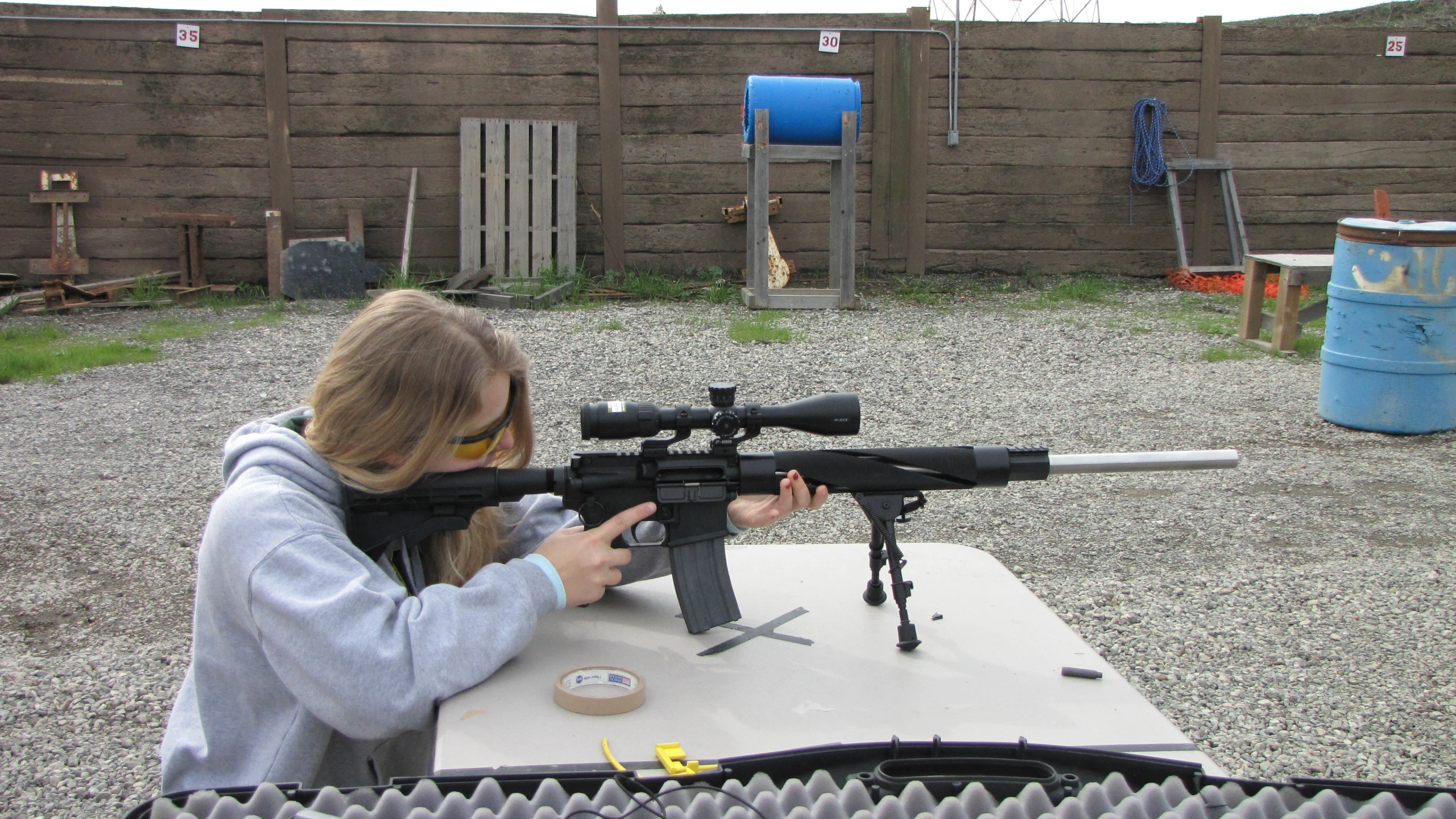 a girl with long blond hair holding a rifle