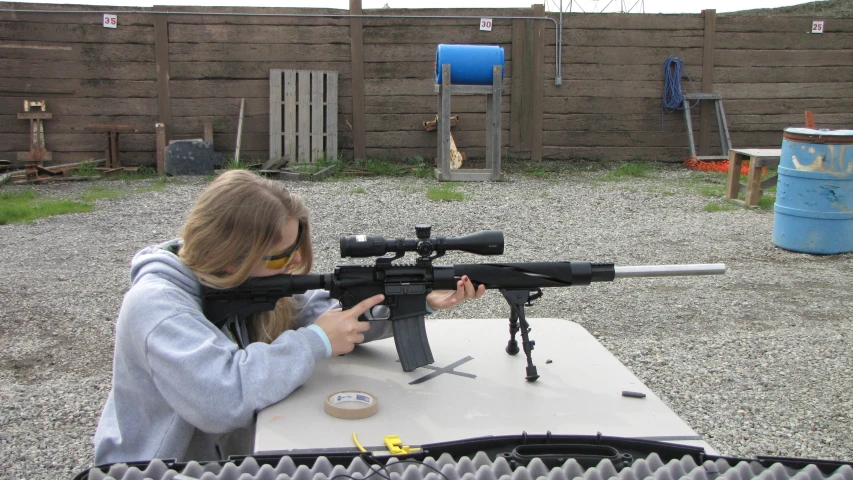 a girl with long blond hair holding a rifle