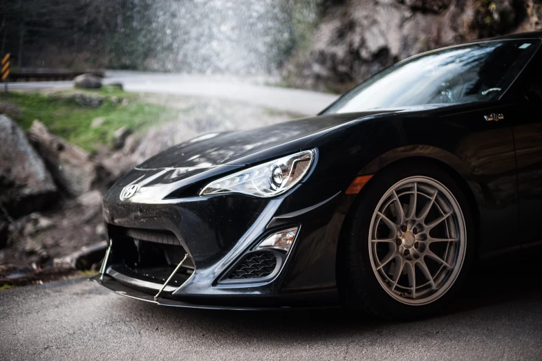 a black sports car is parked in front of a waterfall