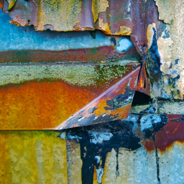 a rusted metal wall that has several colors on it