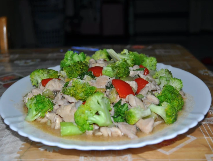 a plate full of broccoli and chicken with tomatoes on it