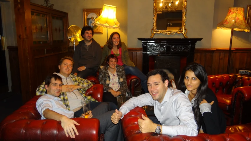 several people sitting in red chairs smiling in front of them