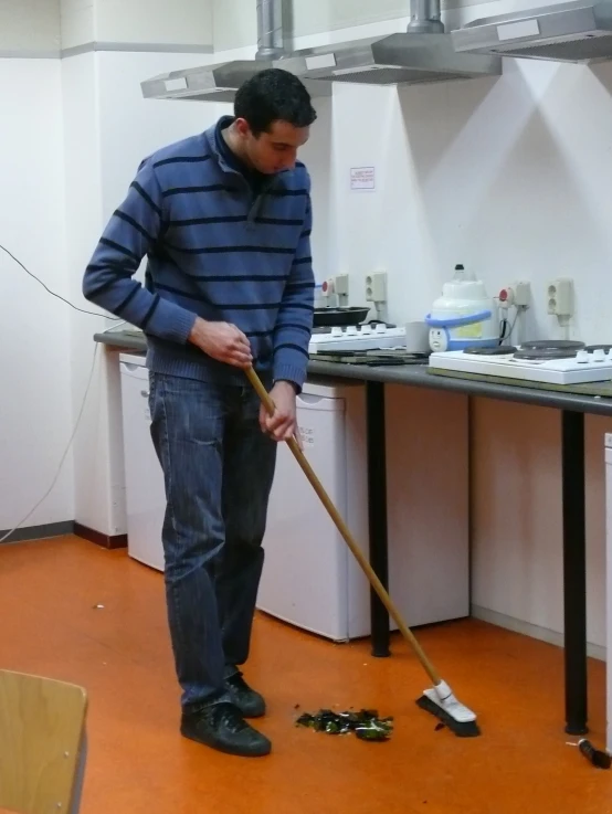 a man is cleaning a kitchen floor with a mop