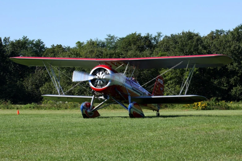 an old red and white airplane sits on grass