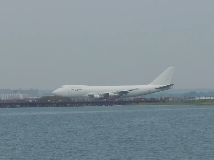 a large white plane that is on the edge of some water