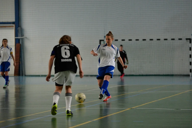 group of women playing soccer together in gym