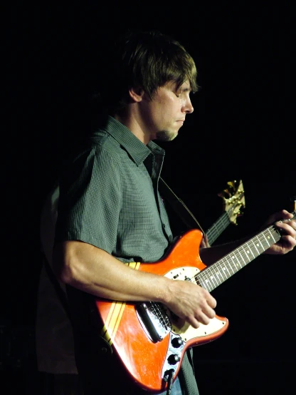 a man with an orange guitar in his hands