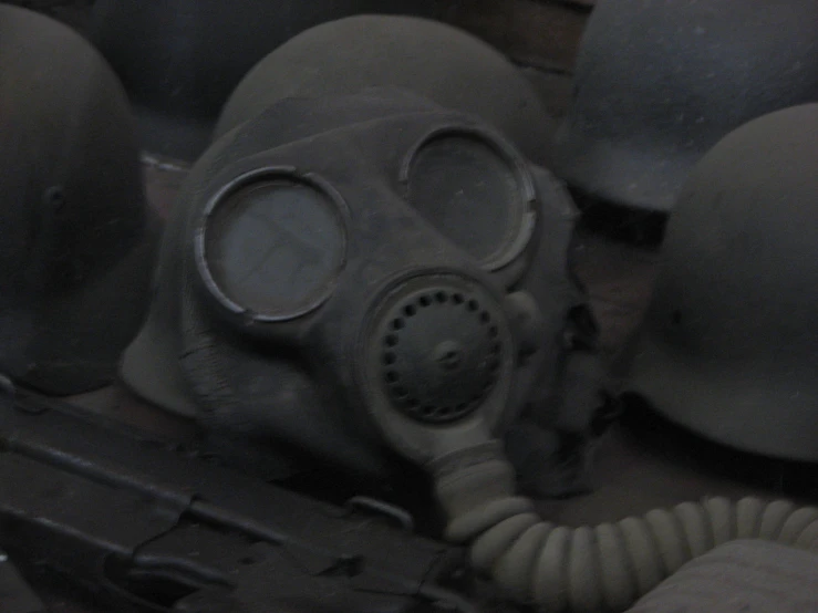 a gas mask is shown in front of army helmets