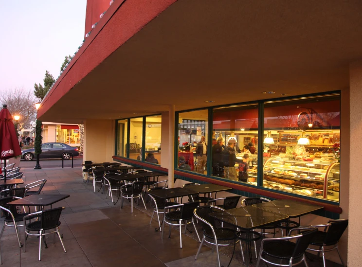 several tables outside of a cafe with umbrellas on the sidewalk