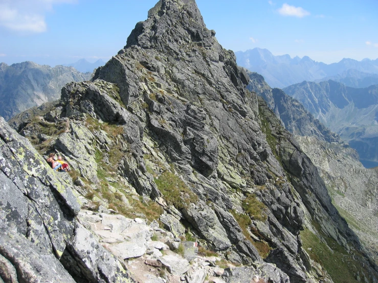 a man in yellow jacket and white hat on the side of a mountain