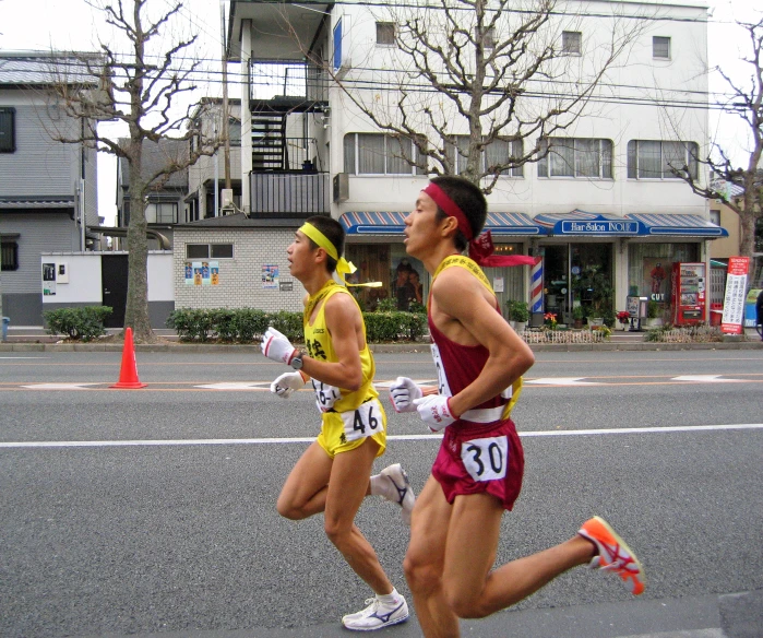 two women are running in the street, one is wearing a red and yellow outfit