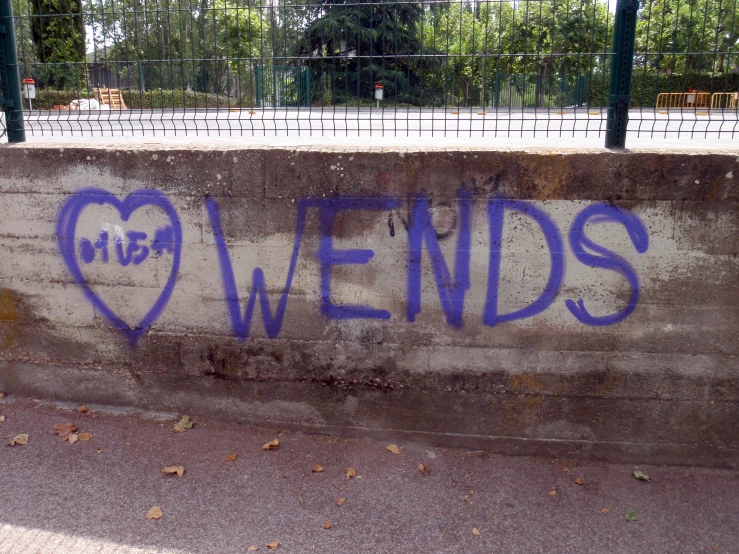 a graffitti - covered wall with words on it and heart - shaped blue letters in between them