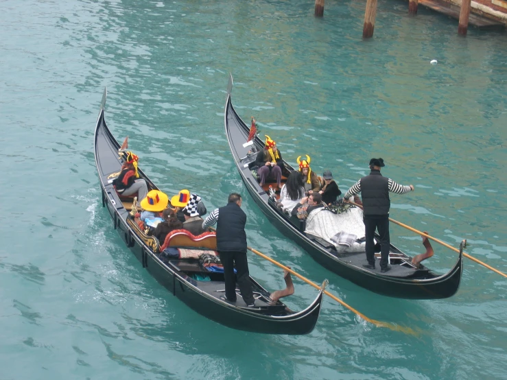 two gondolas are holding people in yellow hats as one man stands near the front of one