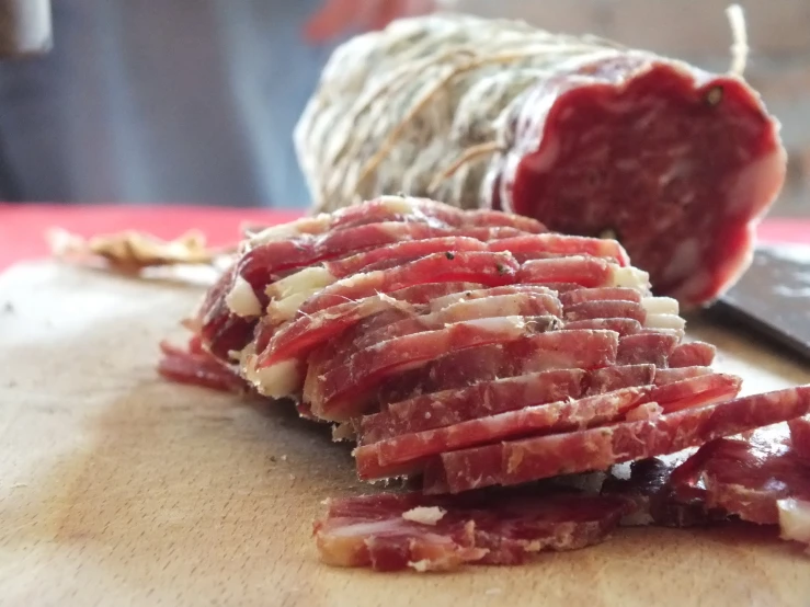 a wooden board that has a large piece of meat on it