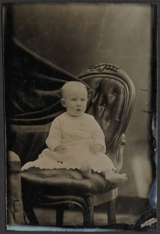 an antique po of a baby sitting on a chair