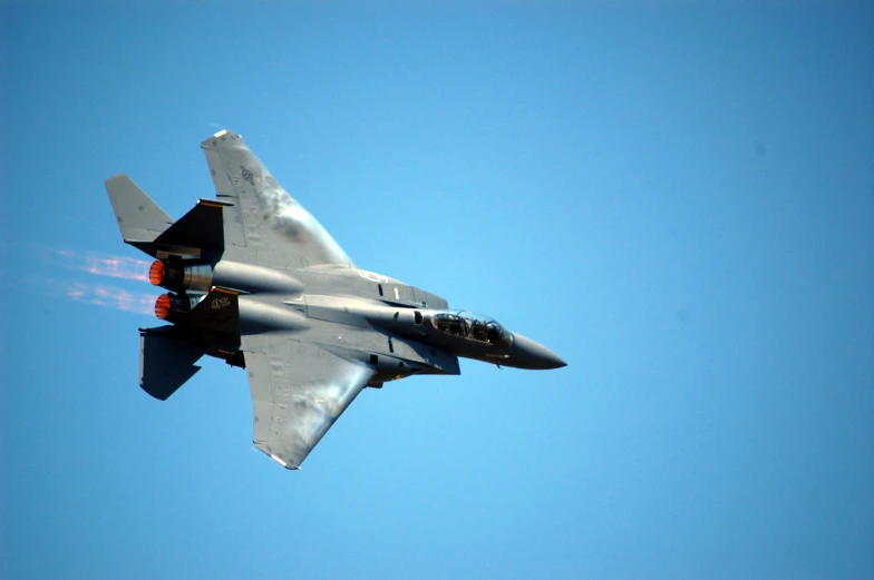 a gray fighter jet flying through a blue sky