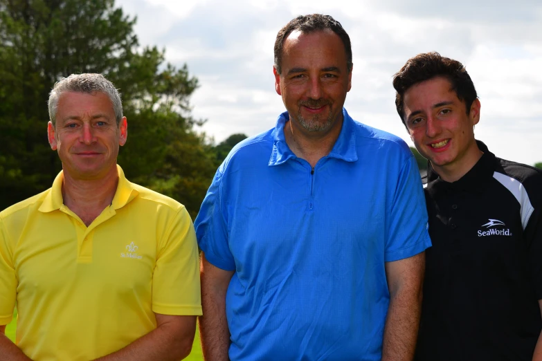 two men with blue collared shirts are smiling