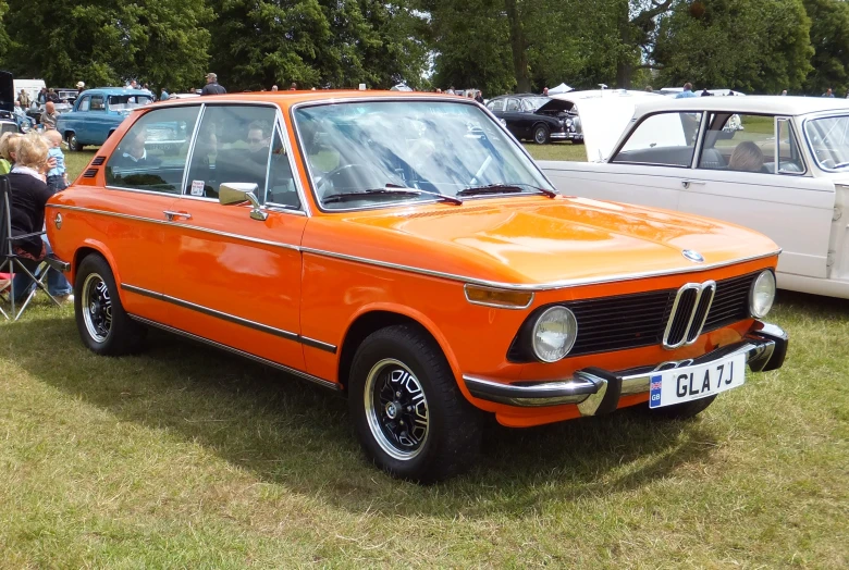 an old bmw is parked at a car show