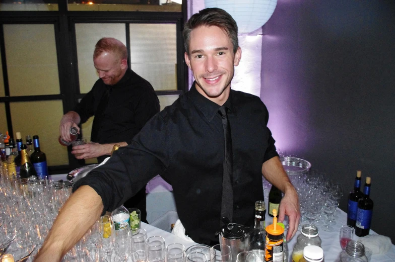 two men sitting at a bar smiling at the camera