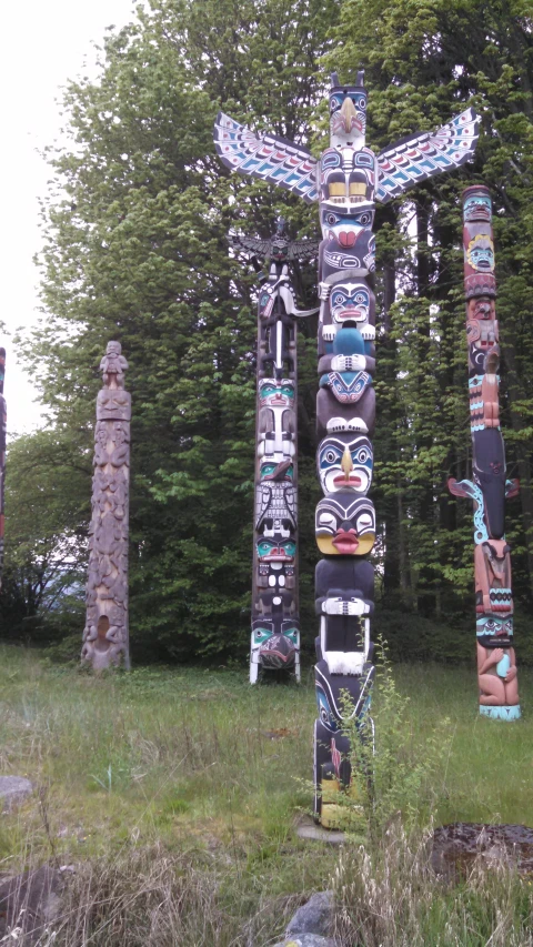 a big group of totem poles in the middle of a field