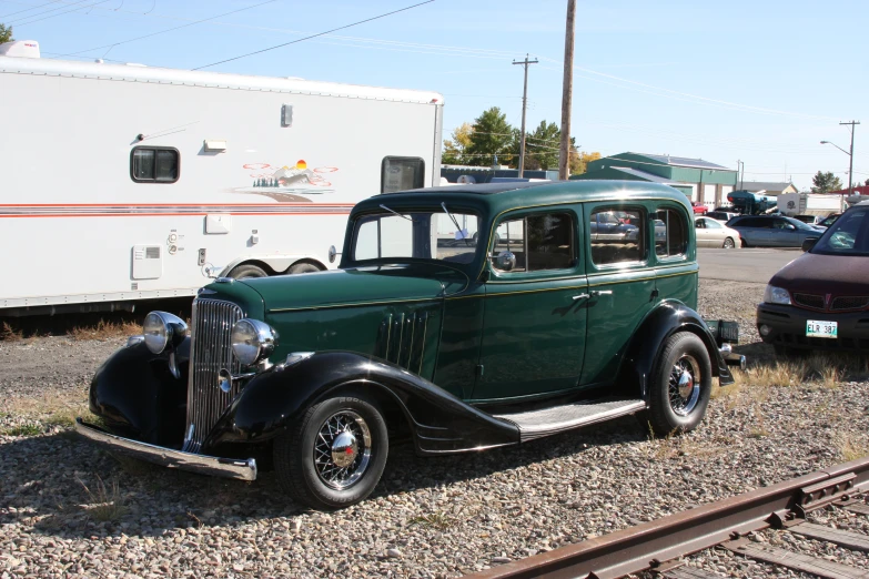 a vintage green car in a gravel lot