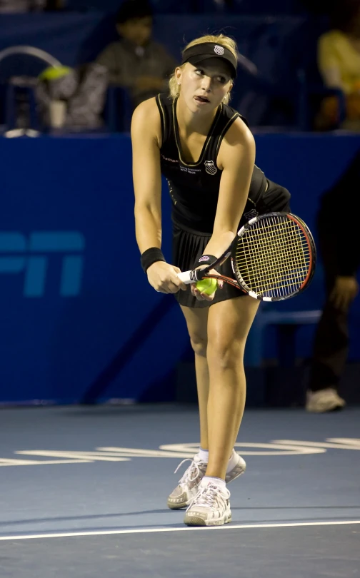 the tennis player in a black top is looking down