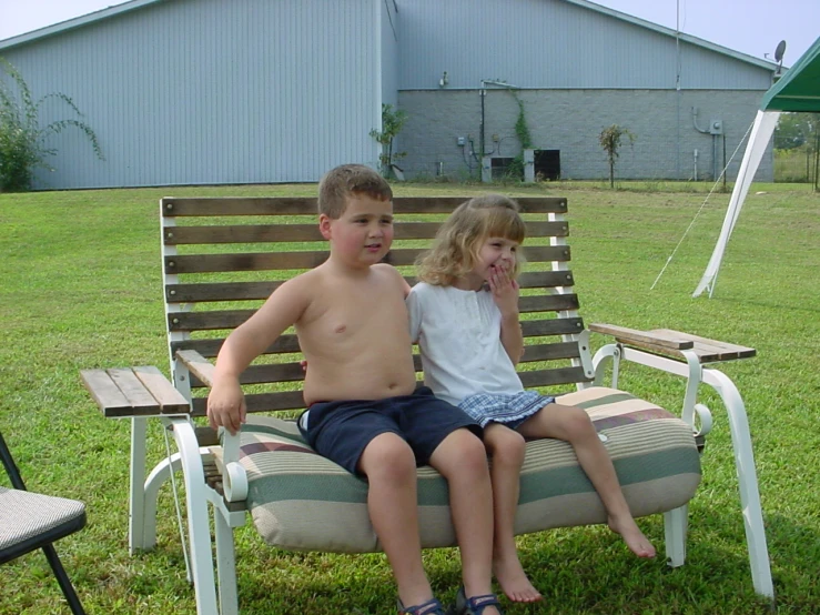 the two children are sitting on the park bench