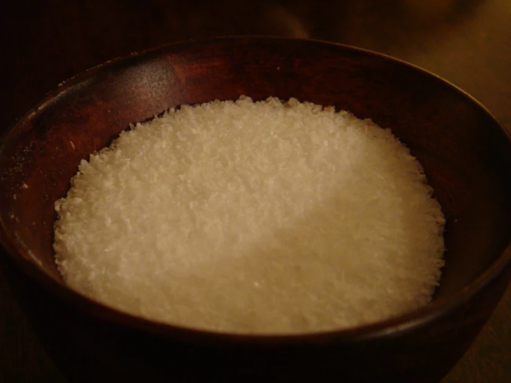 a wooden bowl filled with white rice on top of a table