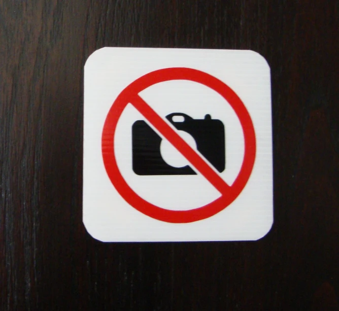 a no camera sign sitting on top of a wooden table