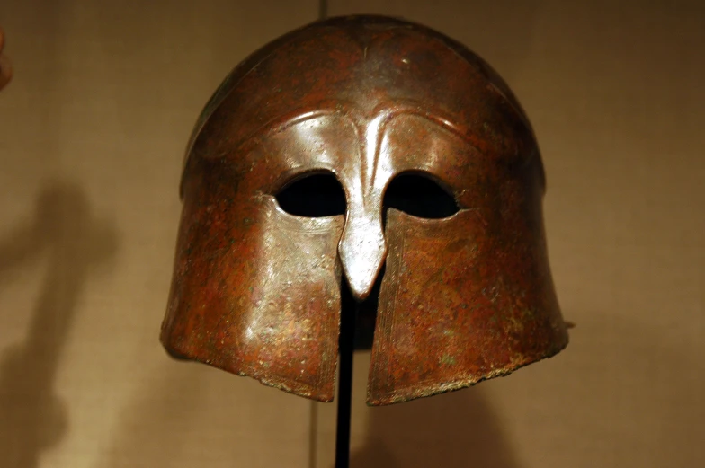 an old, bronze colored mask with an odd shape