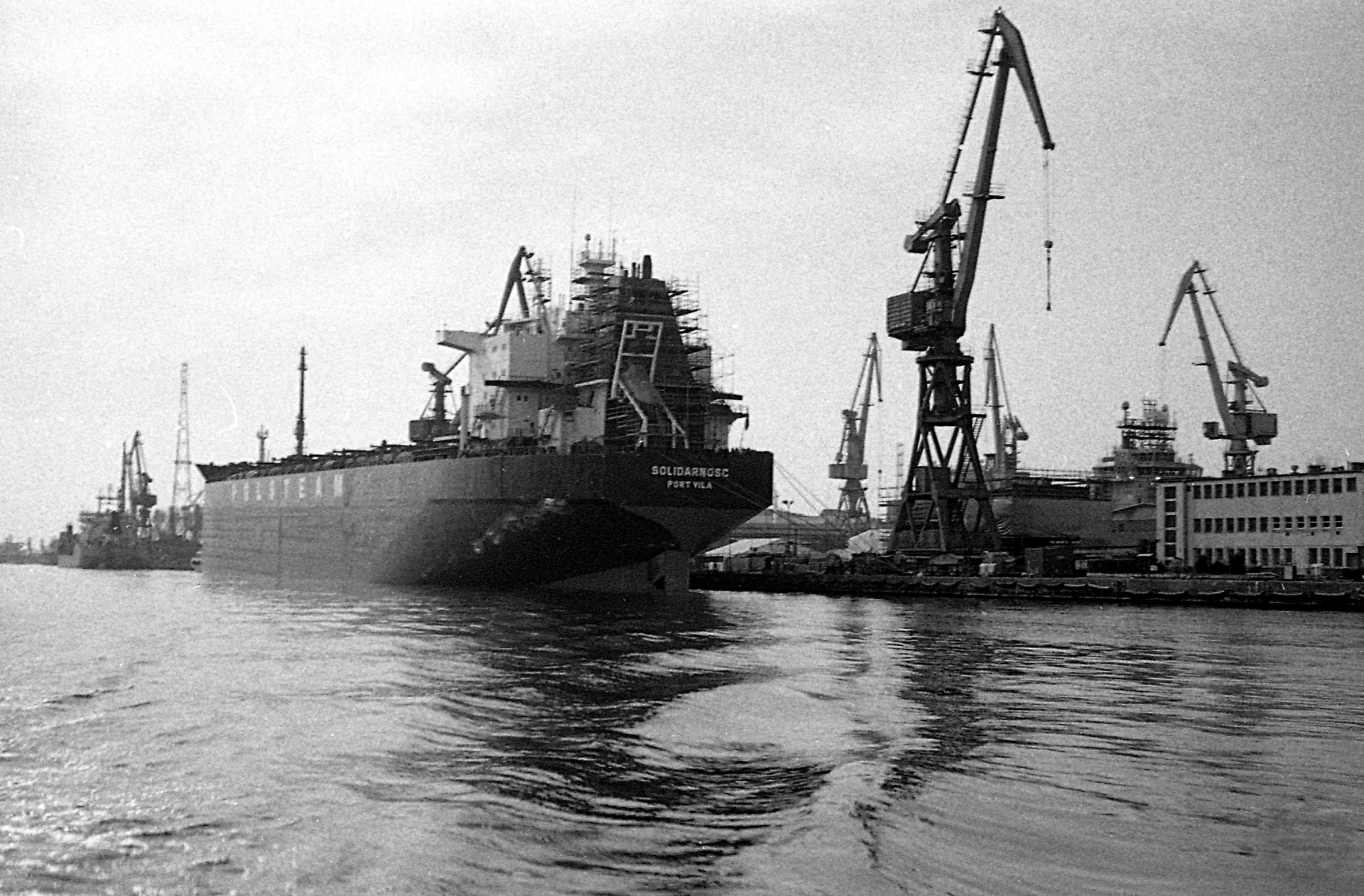 a cargo ship floating on the water near other boats