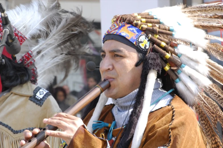 men dressed in native american clothing with flutes