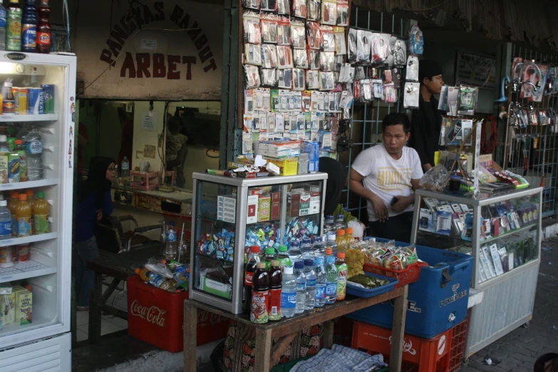 a man is sitting in a small store selling goods