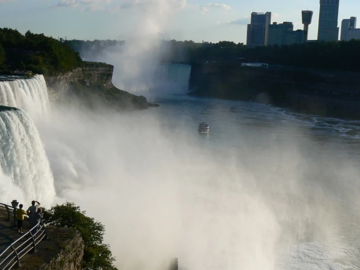 a boat riding by a waterfall with water pouring over it